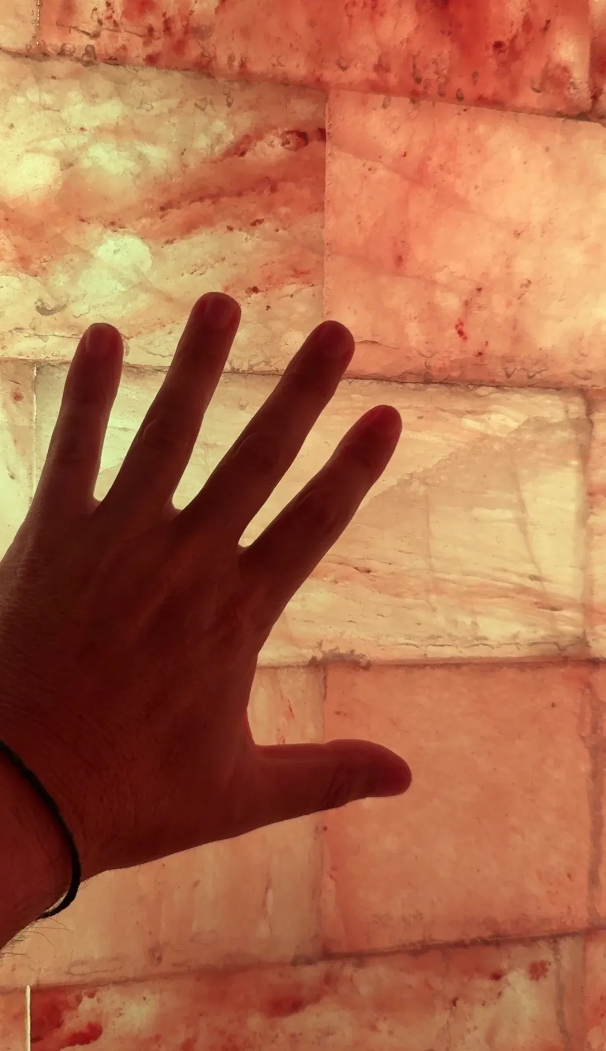 Una mano ante una pared de piedra retroiluminada en tonos cálidos